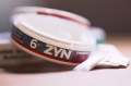 A circular canister that says 'ZYN' on it in all caps.