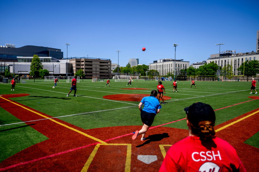 A group of people plays a game on a bright, sunny day.