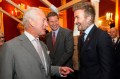 David Beckham greeting King Charles III with a laugh while King Charles III is in the middle of saying something.